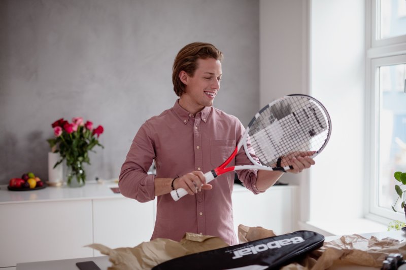 Mann med tennisracket pakket ut av en pakke.