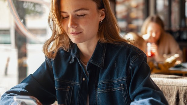 Kvinne ser på mobilen sin og smiler