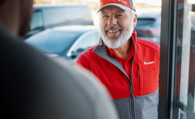 Smilende postbud på døren