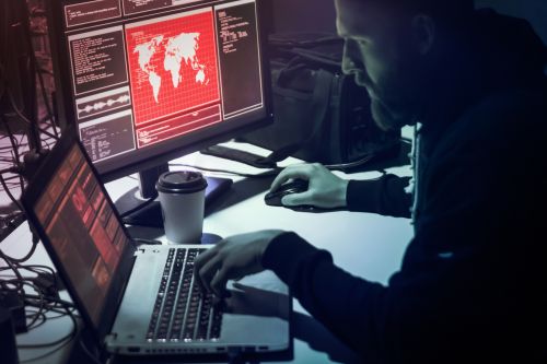 Man in front of computers in a dark room.