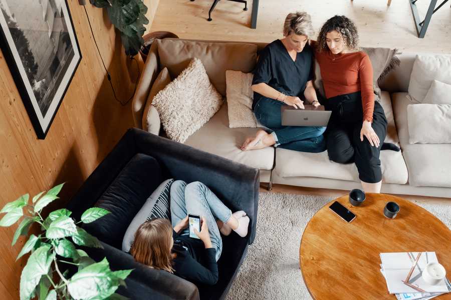 Women on computers in a sofa and a girl on a mobile in a chair