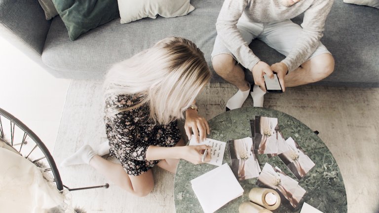 Female writing cards and male looking at a phone