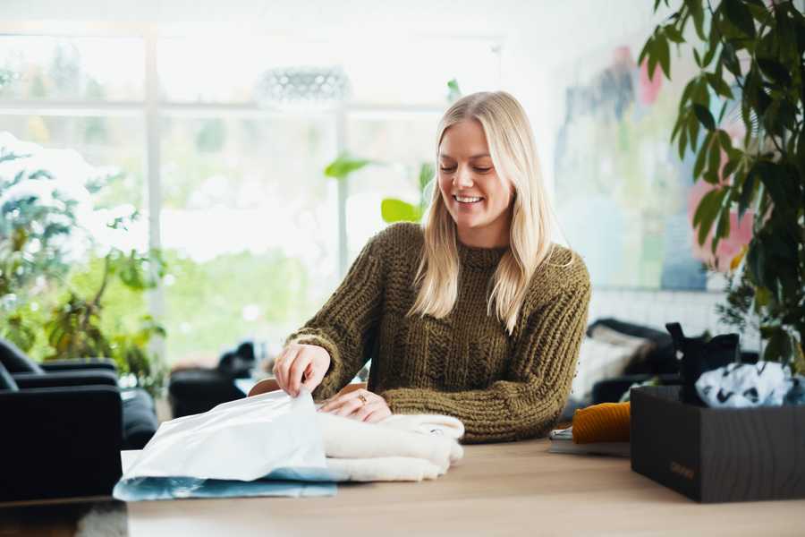 Woman smiling with open parcel at a table