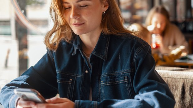 Kvinne ser på mobilen sin og smiler