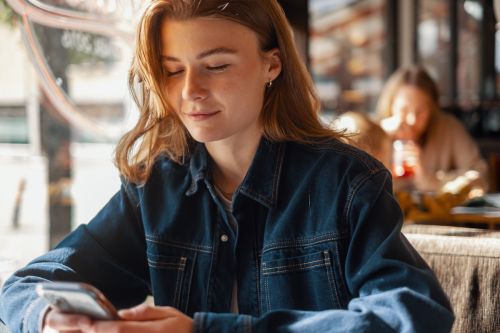 Kvinne ser på mobilen sin og smiler
