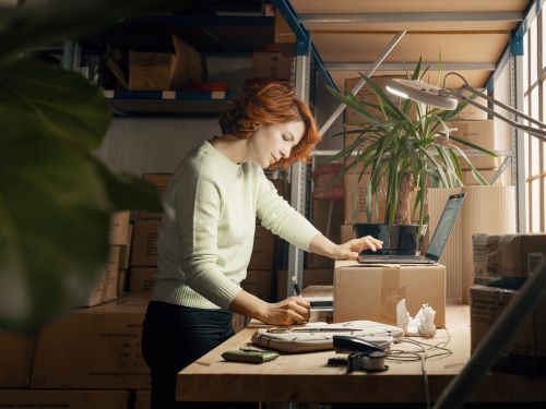 Kvinne med laptop og en pakke som skal sendes