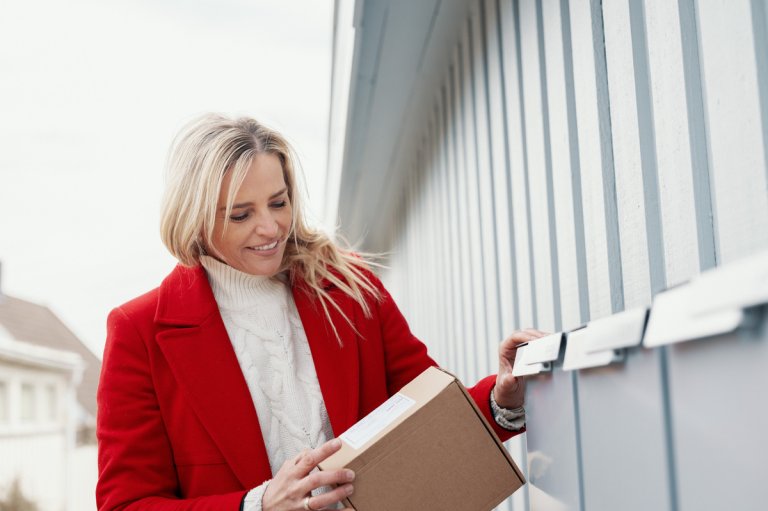 Kvinne med pakke ved postkasse