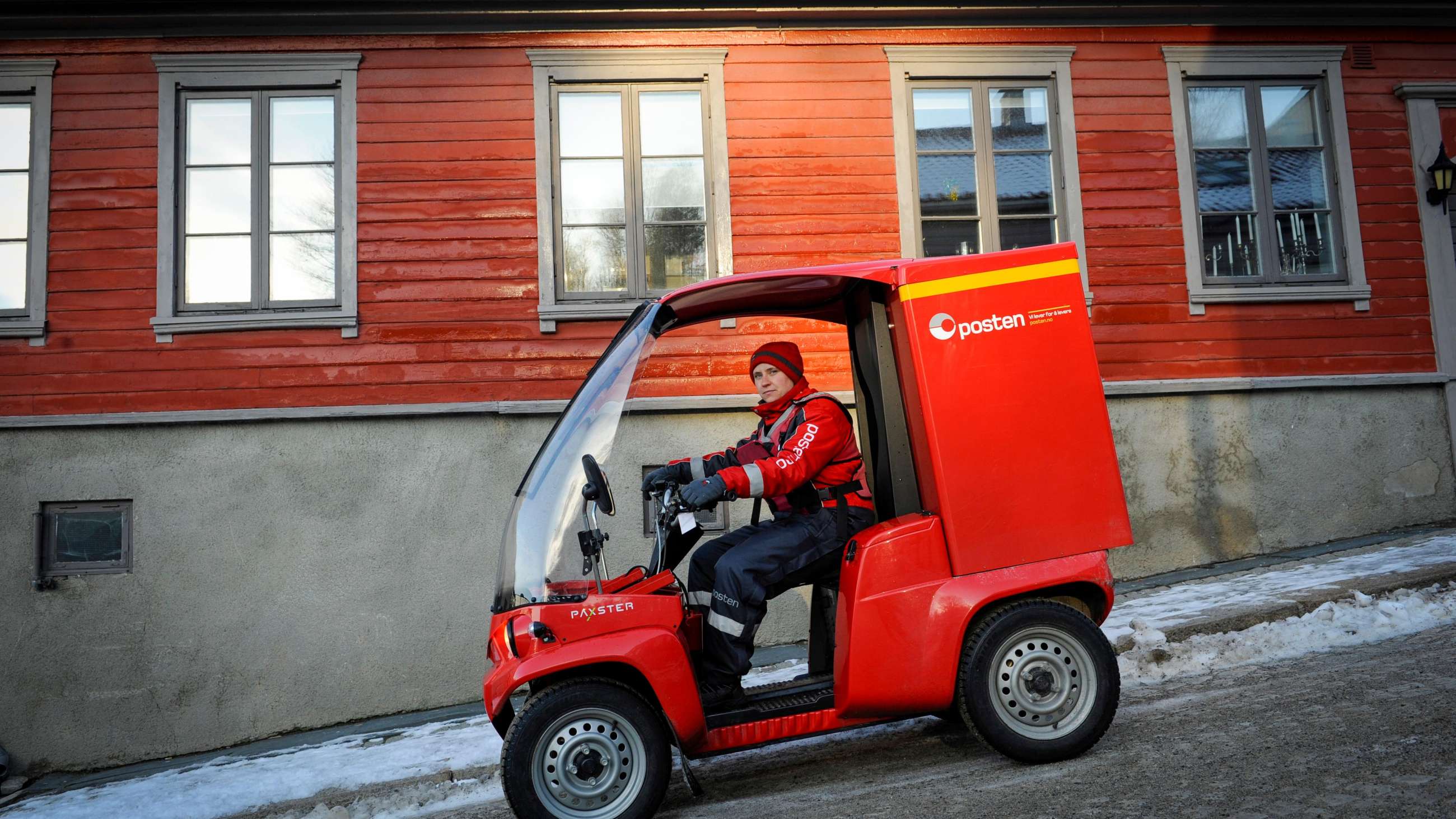 Postbud som sitter i en rød Paxster.