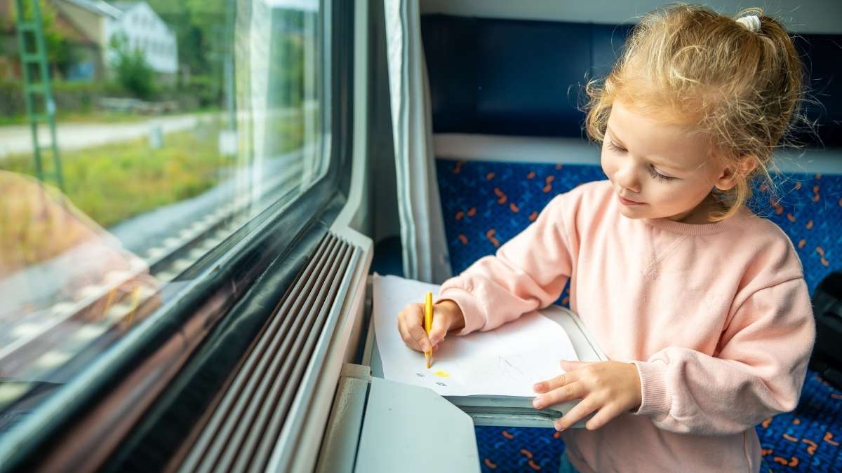Liten jente på et tog som tegner en tegning