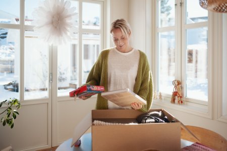 Kvinne i julepyntet hus, ser på innhold i en eske