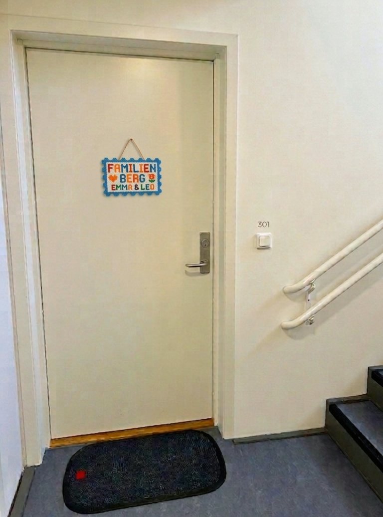 Inngangsdør i oppgang med fargerikt dørskilt