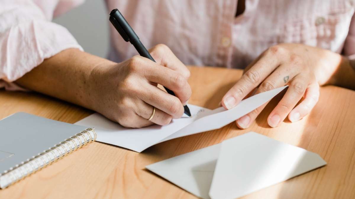 Hender skriver på takkekort