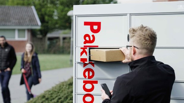 Mann med briller henter en pakke i Pakkeboks