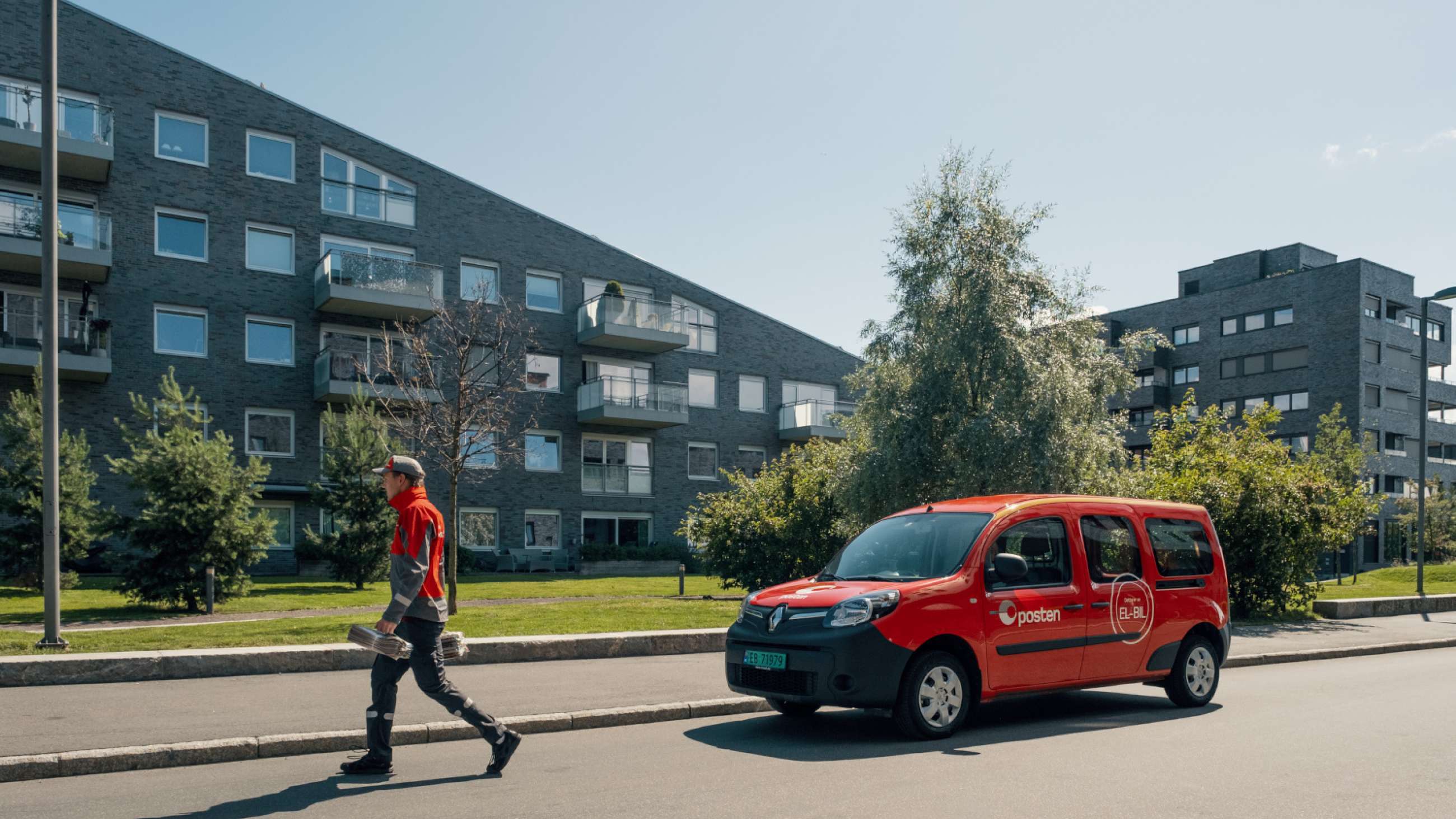 Postbil og bud leverer post i urbant strøk