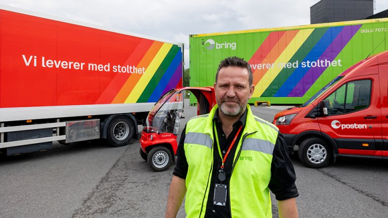 Mann i gul vest foran kjøretøy fra Posten Bring, prydet med regnbuelogo