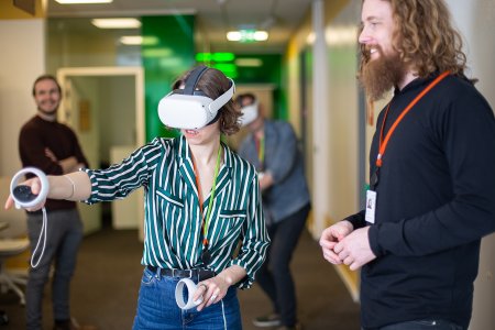 Arbeidsmiljø. En kvinne har på seg VR-briller og beveger hendene med fjernkontroller.