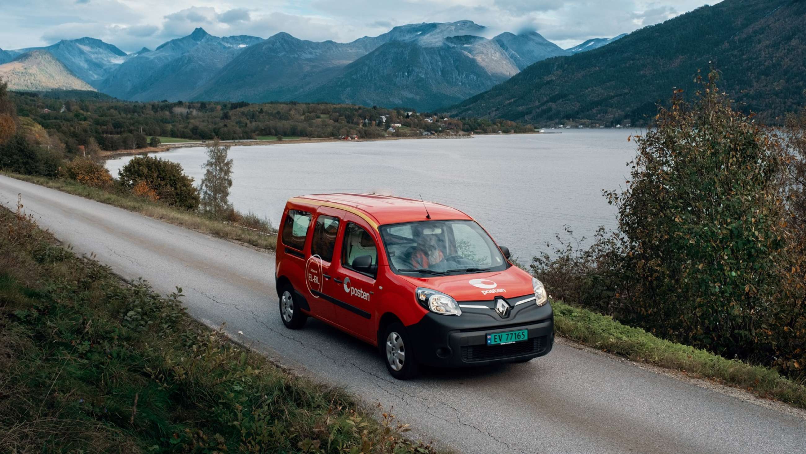 Elbil fra Posten på landevei foran norsk natur med fjell og vann