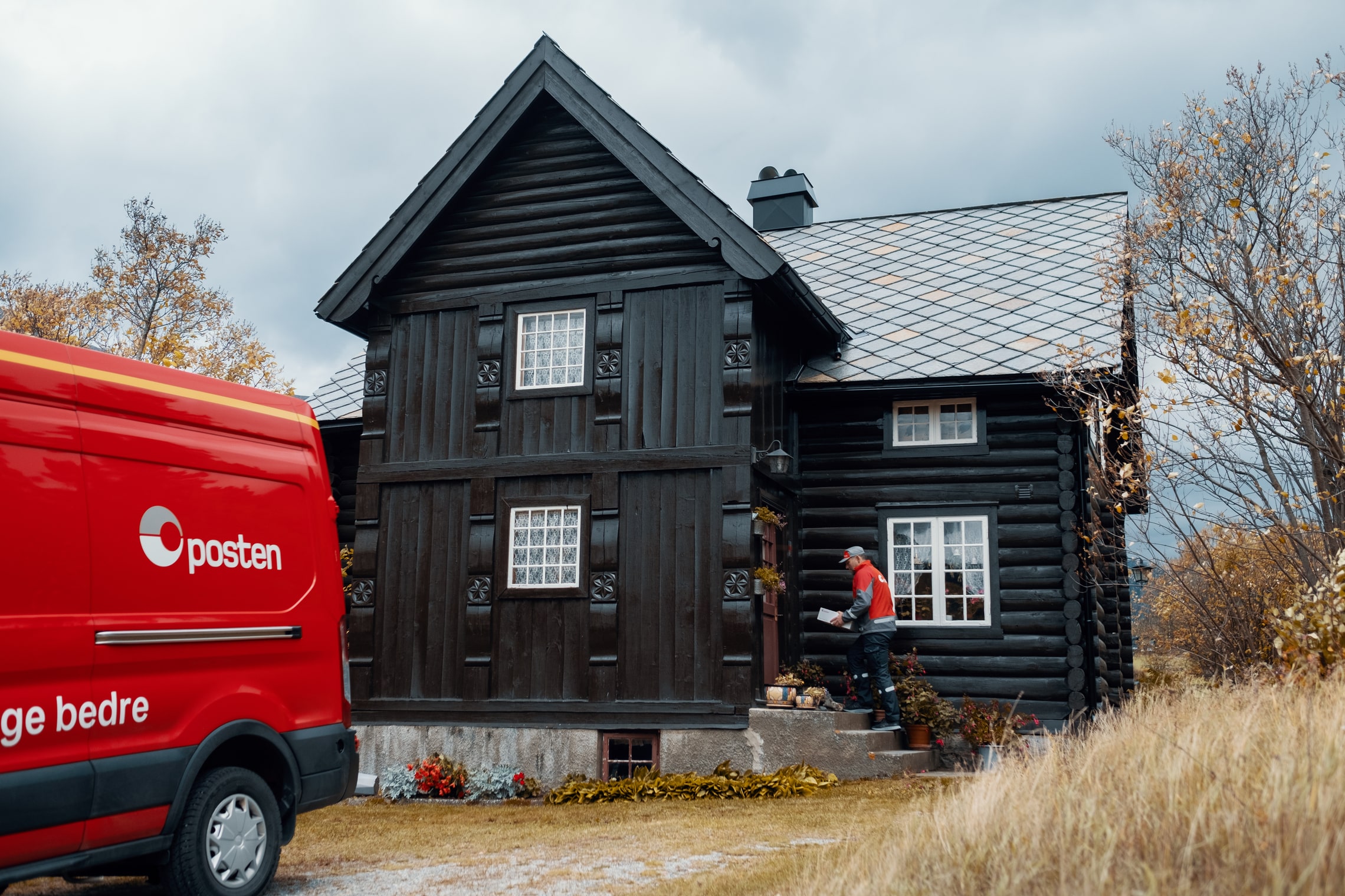 Postbud leverer pakke på dør i et stort hus