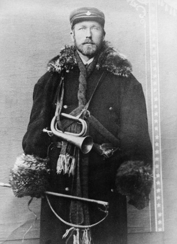 Bilde fra slutten av 1800-tallet av postfører Brataasen, kledd i stor frakk og postlue, med posthorn rundt halsen.
