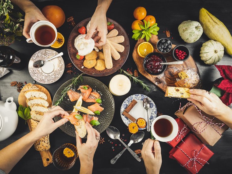 Bord med forskjellige matvarer, og hender som forsyner seg.