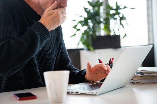 Forskrekket mann holder seg for munnen og ser på sin datamaskin.