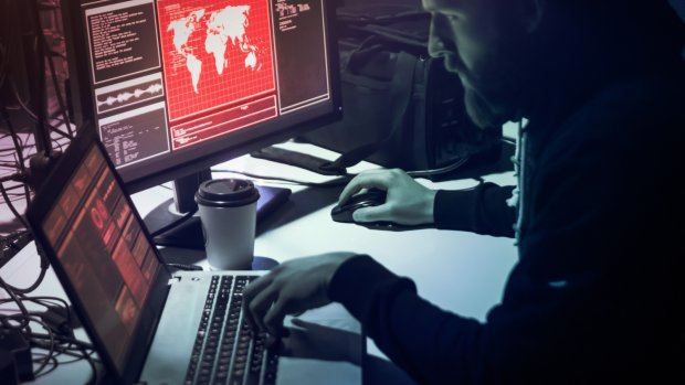 Mann foran datamaskiner i et mørkt rom.