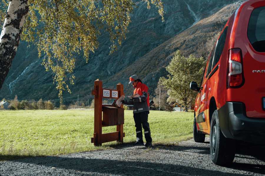 Postbud leverer post i postkasser i landlige omgivelser