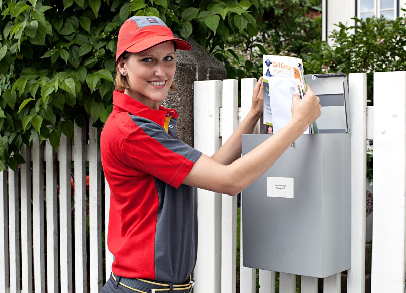 Postbud som leverer post i en postkasse
