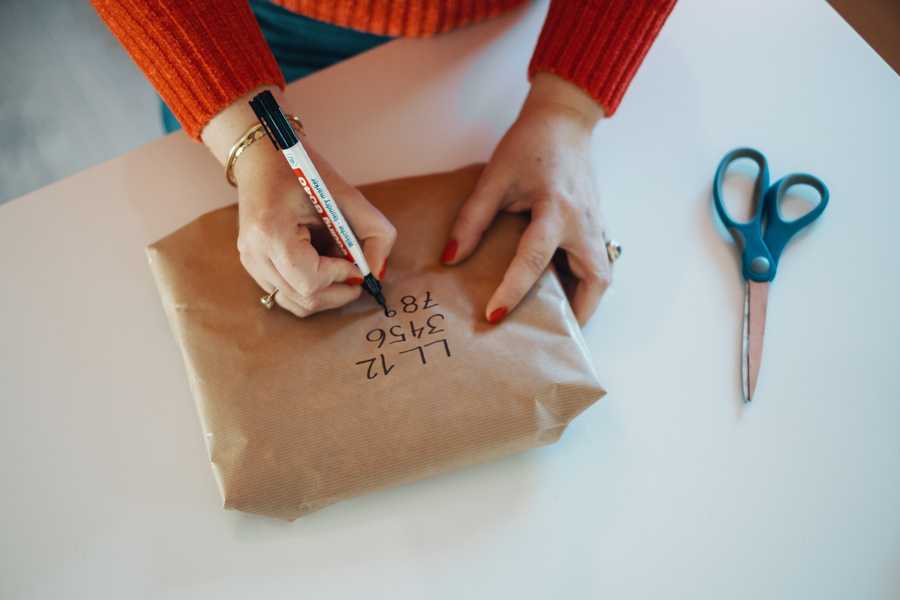 Skriver sendekode på en pakke i brunt papir.
