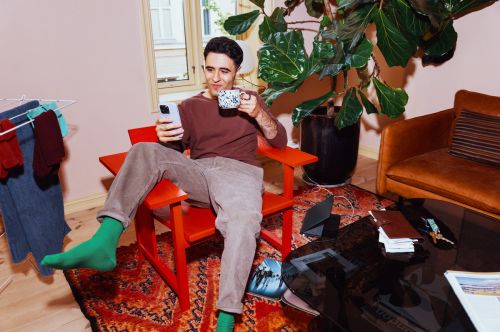 Fornøyd mann med mobiltelefon og kaffekopp