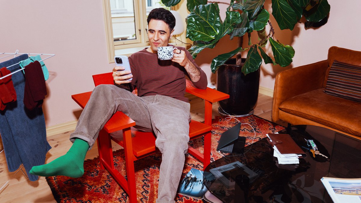 Fornøyd mann med mobiltelefon og kaffekopp